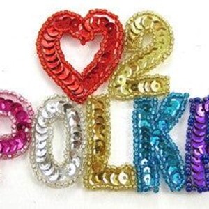 May include: Sequin iron-on patches in the shape of a heart and the letters "POLKA" in various colors, including red, gold, pink, silver, blue, and purple.