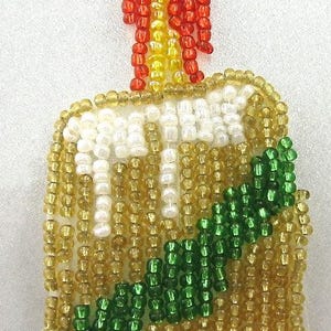 May include: A beaded candle ornament with a flame. The candle is made of gold beads with a white wax top and a green ribbon. The flame is made of red, yellow, and orange beads. This festive decoration is perfect for the holidays.