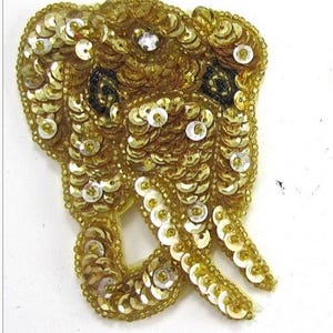 May include: Gold sequined elephant applique. The elephant is made of gold sequins and has a detailed design.