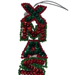 May include: A Christmas ornament shaped like the word "XMAS" made of red and green sequins.