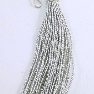 May include: A silver tassel with a loop at the top. The tassel is made of many thin strands of silver thread.