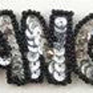 May include: Black and silver sequined iron-on patch that says "DANCE" in large, bold letters.