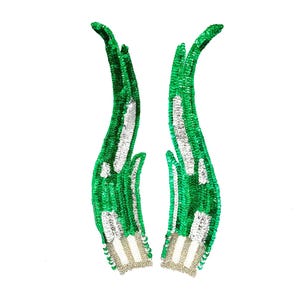 May include: Two green sequined hand-shaped appliques with silver accents. The appliques are detailed with silver sequins on the fingers and wrist area. The hands are curved upwards, giving a graceful appearance.