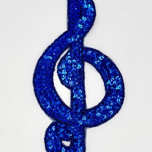 May include: A blue sequined treble clef music note patch.