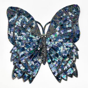 May include: A large iridescent blue butterfly applique made of sequins. The butterfly is a popular motif for embellishing clothing, bags, and other accessories.