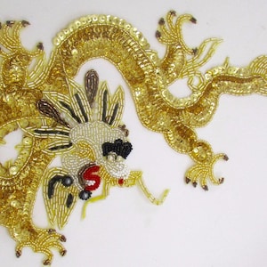 May include: A gold sequined dragon applique with black and white bead accents. The dragon is curled up with its head facing the left.