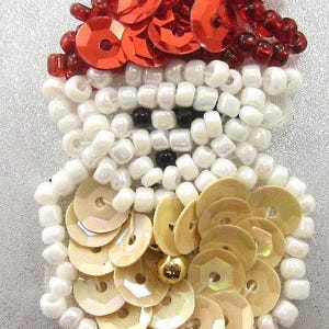 May include: A white beaded snowman with a red sequin hat and a gold bead nose. The snowman is decorated with white and gold sequins.