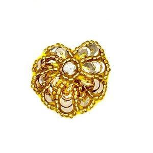May include: A circular embroidered patch featuring a bright yellow felt base adorned with metallic gold sequins and small gold beads. The centre of the patch is highlighted by a single clear, faceted rhinestone surrounded by a ring of gold beads.