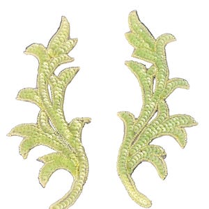 May include: A pair of light lime green embroidered appliques featuring a dense covering of small, circular sequins arranged in a scrolling, leafy, or vine-like pattern with curved edges and pointed tips, designed for decorative textile embellishment.