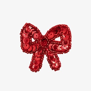 May include: A red sequined bow, possibly for clothing or accessories. The bow is detailed with small, round sequins, creating a shimmering effect. The design is symmetrical, with loops and tails, and is set against a white background.