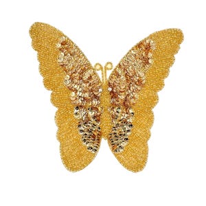 May include: A golden butterfly-shaped embellishment. The wings are covered in small, gold beads and sequins. The butterfly has a detailed design with a textured appearance, perfect for adding a decorative touch to clothing or accessories.