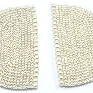 May include: Two ivory-colored, half-circle shaped embellishments, densely covered with small, round faux pearls. The pearls are arranged in concentric rows, creating a textured surface. The embellishments are set against a plain white background.