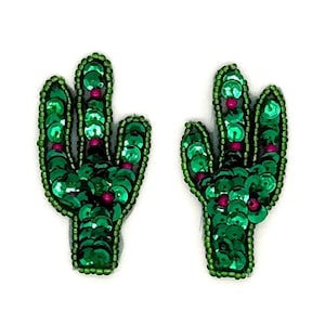 May include: Two cactus-shaped patches featuring vibrant green sequins and small magenta beads. The edges of each patch are outlined with tiny green seed beads, creating a defined silhouette for these decorative textile embellishments.