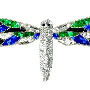 May include: A dragonfly-shaped patch embellished with sequins in silver, bright green, royal blue, and black. The body is covered in silver sequins, while the wings feature a segmented pattern of green, blue, black, and silver sequins with beaded edges.