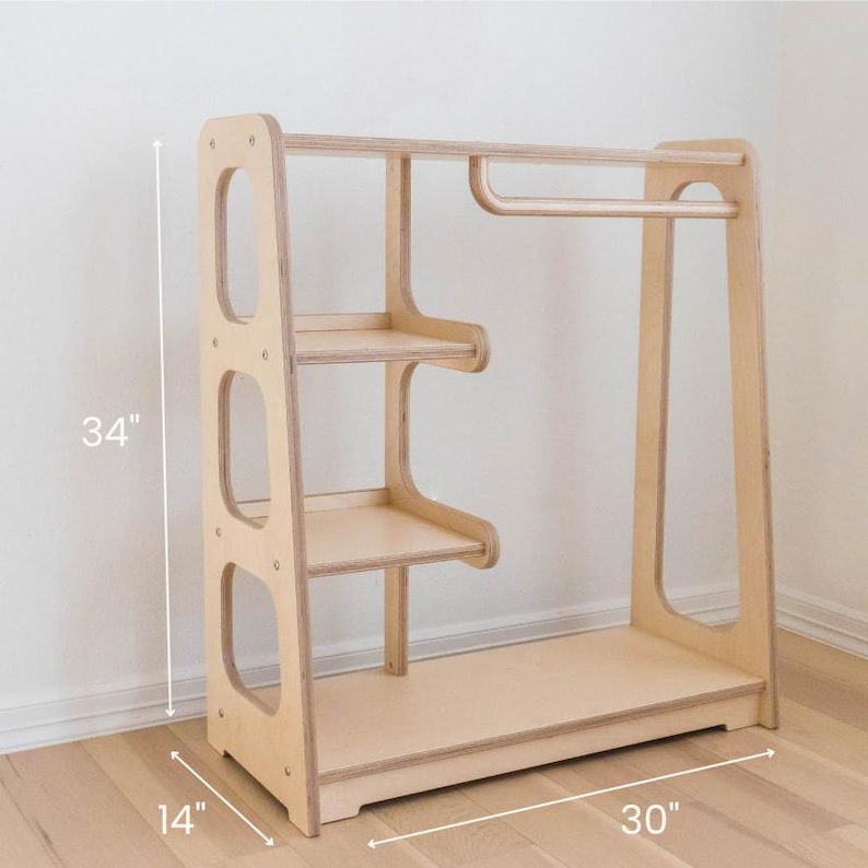 K&ouml;nnte beinhalten: Ein Kleiderst&auml;nder aus Holz mit drei Regalen und einer Kleiderstange. Der St&auml;nder ist 86 cm hoch, 76 cm breit und 36 cm tief.