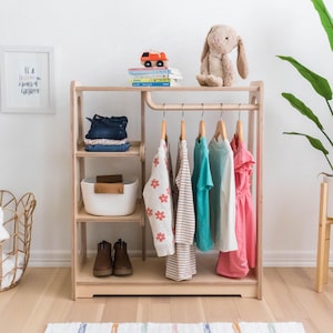 Kids wooden wardrobe that has an open shelf design and a curved rod to hang up on hangers. Montesorri inspired warm colors.