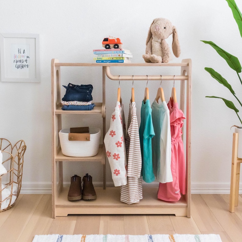 Kids wooden wardrobe that has an open shelf design and a curved rod to hang up on hangers. Montesorri inspired warm colors.
