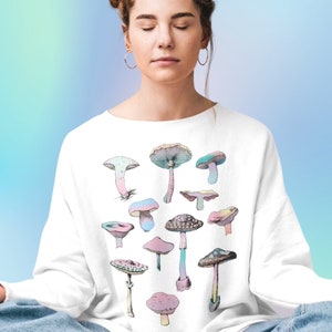 May include: White sweatshirt with a colorful mushroom graphic print. The mushrooms are in various shades of pink, blue, and green.