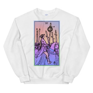 May include: White sweatshirt with a colorful illustration of the Six of Wands tarot card. The card features a rider on horseback with a wreath of laurels on a staff.