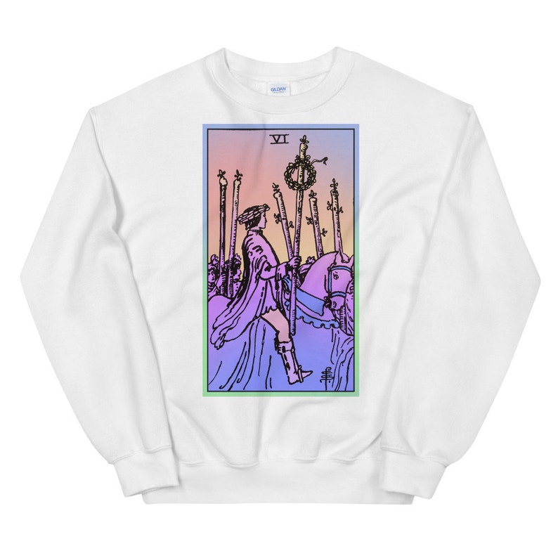 May include: White sweatshirt with a colorful illustration of the Six of Wands tarot card. The card features a rider on horseback with a wreath of laurels on a staff.