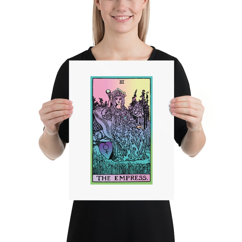 May include: A framed print of a tarot card, "The Empress." The artwork features a seated figure with a crown, scepter, and a heart symbol. The background has a gradient of pink, yellow, and blue. The text "THE EMPRESS" is at the bottom.