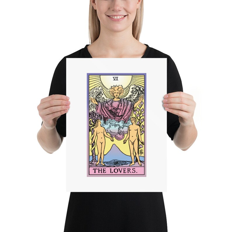 May include: The Lovers tarot card, featuring a winged angel above two nude figures standing on either side of a mountain. The card is framed in a white border and has a pink and purple gradient background.