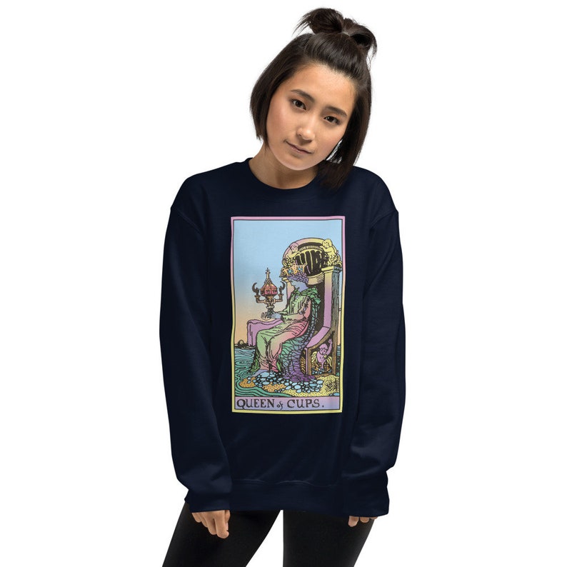 Puede incluir: Sudadera azul marino con una ilustraci&oacute;n colorida de la carta del tarot de la Reina de Copas. La carta representa a una mujer sentada en un trono con una copa en la mano. El texto "QUEEN of CUPS." est&aacute; impreso debajo de la carta.