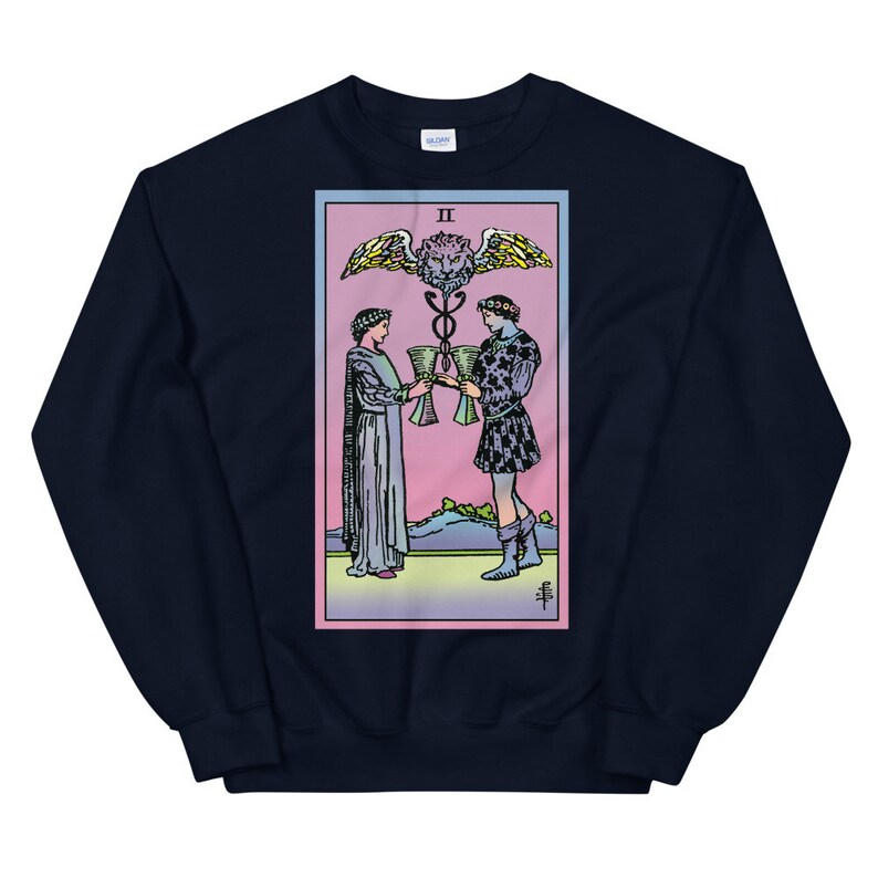 May include: Navy blue sweatshirt with a colorful illustration of the Two of Cups tarot card. The card features two figures holding cups, a winged serpent, and the Roman numeral II.