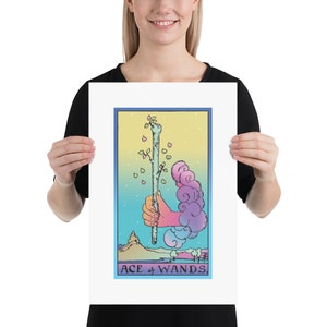May include: A pastel-colored tarot card illustration of the Ace of Wands. The card features a hand holding a wand with a small plant growing from the top. The background is a gradient of blue, yellow, and pink.
