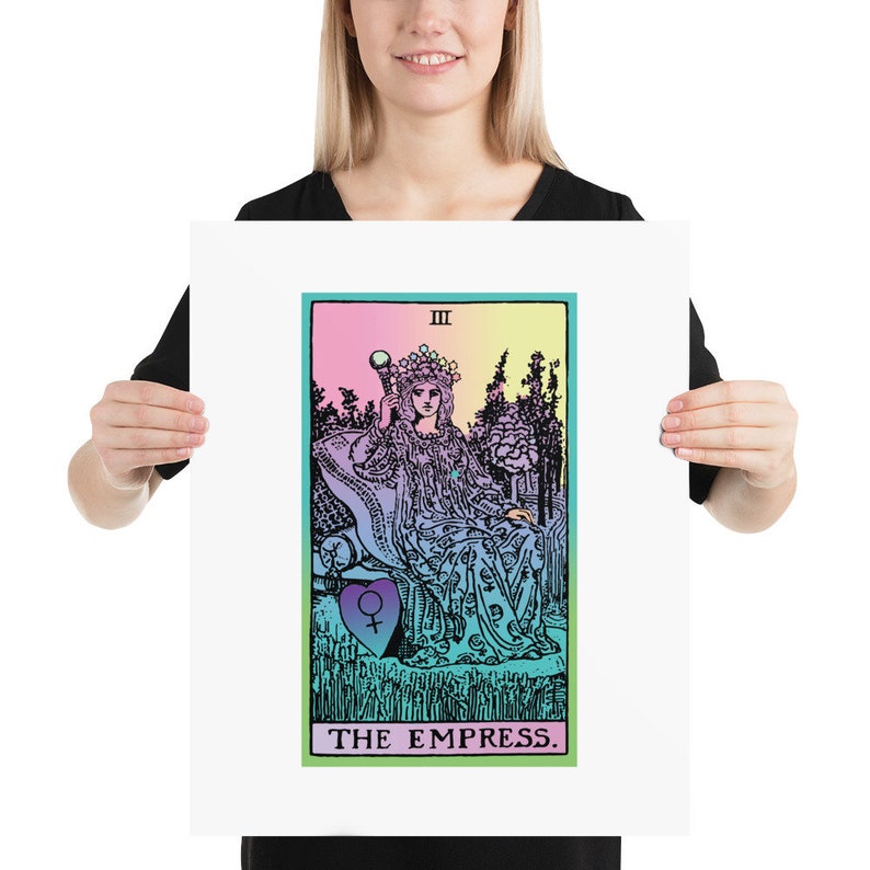 May include: A framed print of The Empress tarot card. The artwork features a woman in a flowing gown, holding a scepter, and wearing a crown. The background is a gradient of pink, yellow, and blue. The text "THE EMPRESS" is at the bottom.