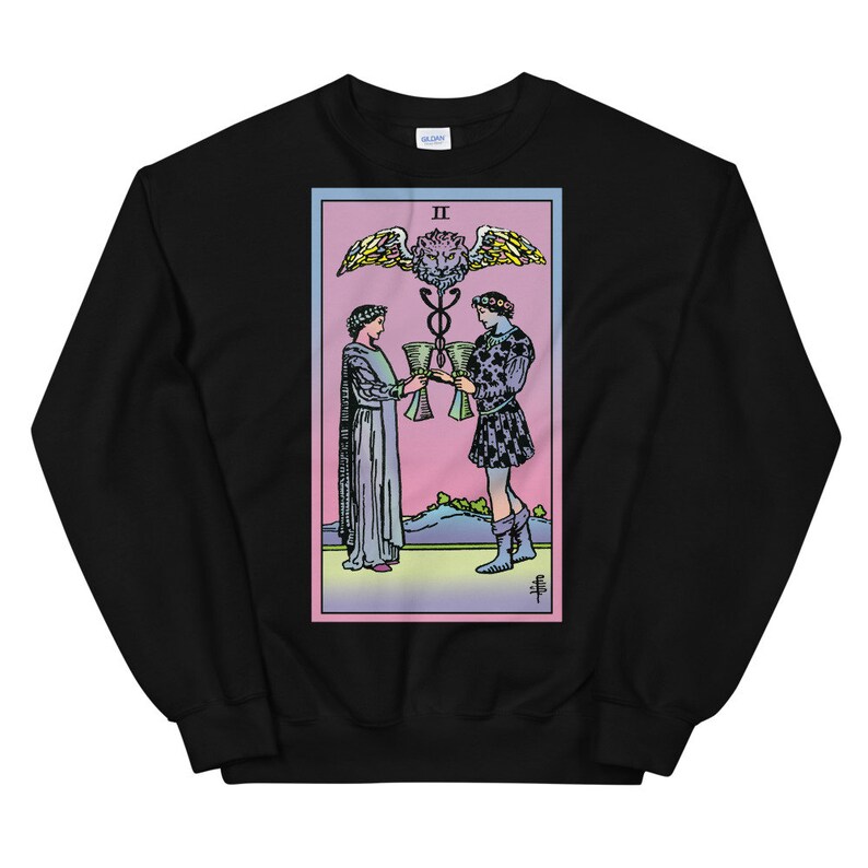 May include: Black sweatshirt with a colorful illustration of the Two of Cups tarot card. The card features two figures holding cups, a winged serpent, and the Roman numeral II.