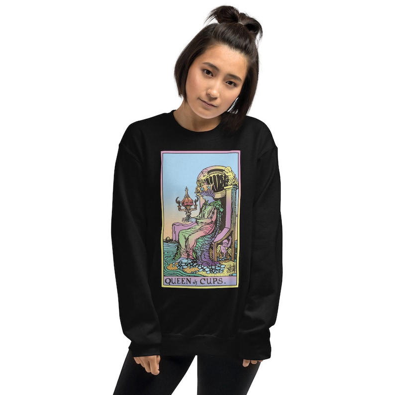 Puede incluir: Sudadera negra con una ilustraci&oacute;n colorida de la carta del tarot de la Reina de Copas. La carta representa a una mujer sentada en un trono con una copa en la mano. El texto "QUEEN of CUPS." est&aacute; impreso debajo de la carta.