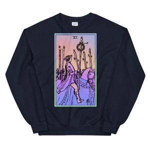 May include: A navy blue sweatshirt with a colorful illustration of the Six of Wands tarot card. The card features a rider on horseback, holding a staff with a wreath on top, surrounded by five other staffs.