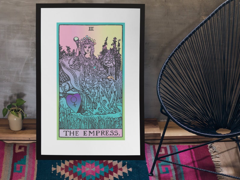 May include: A framed print of The Empress tarot card. The artwork features a seated figure with a crown, holding a scepter, in a colorful, pastel-toned design. The card's title, "THE EMPRESS," is printed at the bottom. The frame is black.