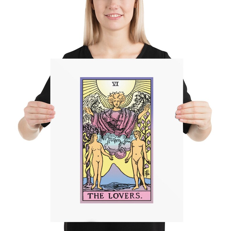 May include: The Lovers tarot card features a colourful illustration of a winged angel above two nude figures standing on either side of a mountain. The card is labelled "VI" and "THE LOVERS."