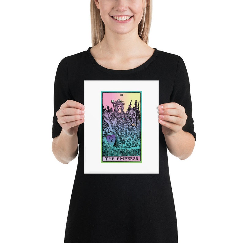May include: A framed print of The Empress tarot card. The artwork features a seated figure in a flowing gown, with a crown and scepter. The card has a colorful design with a green, pink, and blue color scheme. The text "THE EMPRESS" is at the bottom.