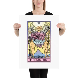 May include: The Lovers tarot card features a colourful illustration of a winged angel with a halo, standing above two nude figures. The card is framed in a white border with the Roman numeral VI and the words "THE LOVERS."