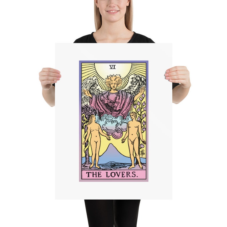 May include: The Lovers tarot card features a colourful illustration of a winged angel with a halo, standing above two nude figures. The card is framed in a white border with the Roman numeral VI and the words "THE LOVERS."