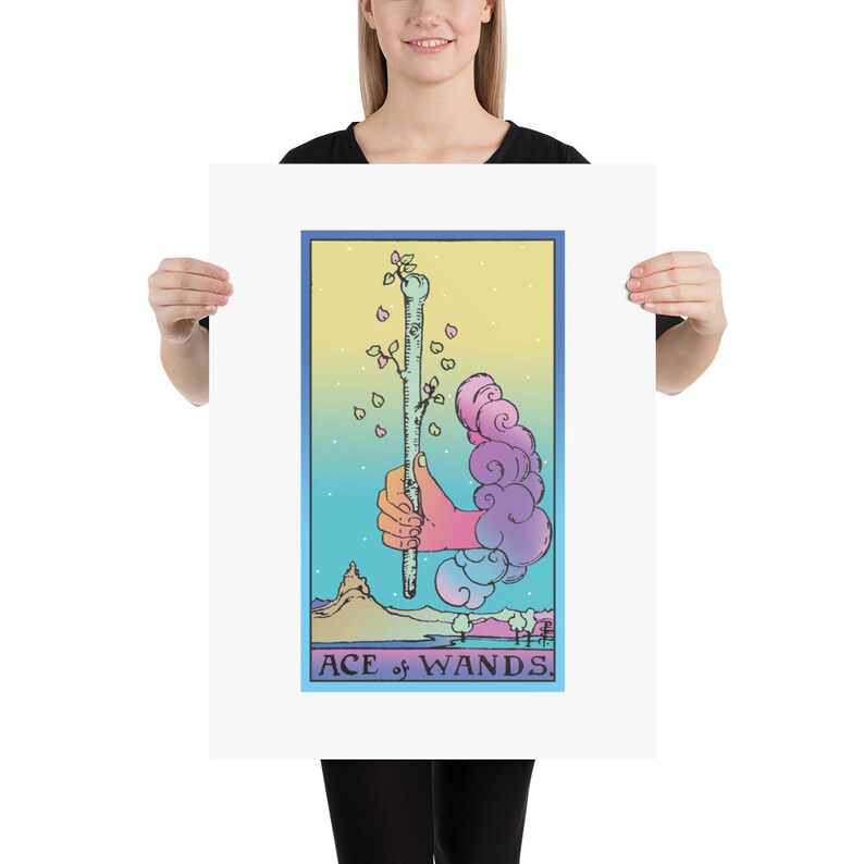 May include: A tarot card illustration of the Ace of Wands. The card features a hand holding a green wand with a small tree growing from the top. The background is a gradient of blue, yellow, and pink with clouds and a mountain in the distance. The text "ACE of WANDS" is printed at the bottom of the card.