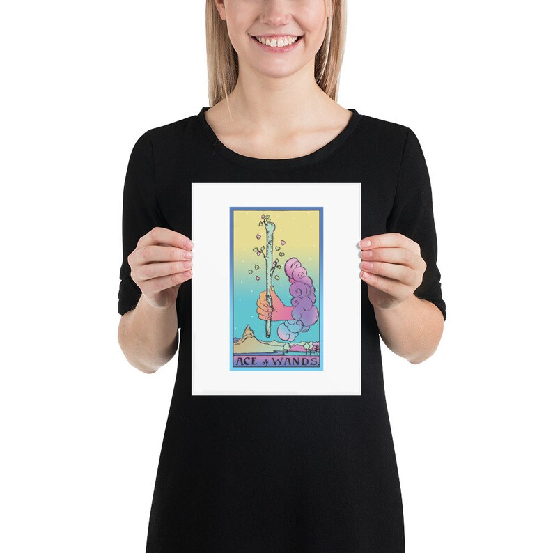 May include: A tarot card print featuring the Ace of Wands. The card depicts a hand holding a wand with leaves growing from it. The background is a colorful gradient of blue, yellow, and pink.