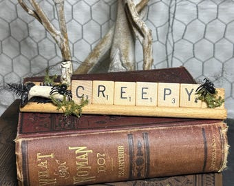 Estantería de decoración de Halloween con fichas de Scrabble alteradas hechas a mano y patas de muñeca vintage.