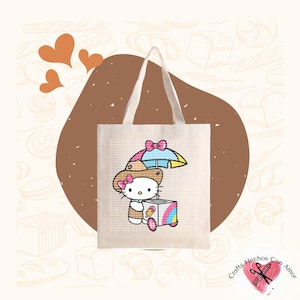 May include: A white canvas tote bag with a colorful illustration of Hello Kitty selling ice cream. The illustration features Hello Kitty wearing a hat and holding an ice cream cone. The bag has a brown handle.