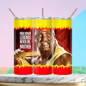 Puede incluir: Tres vasos de acero inoxidable con pajitas. Cada vaso presenta un diseño de Hulk Hogan con el texto "Hulk Hogan Legends Never Die, Brother" sobre un fondo rojo y amarillo. Los vasos están sobre una superficie de mármol.