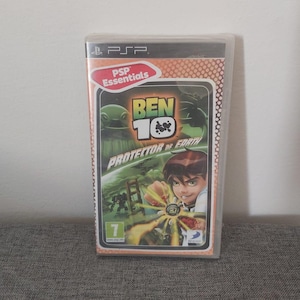 Pode incluir: Uma caixa de jogo PSP com um design vermelho, branco e preto. O jogo é Ben 10: Protector of Earth. A caixa tem um logotipo PSP Essentials e uma classificação de 7+.
