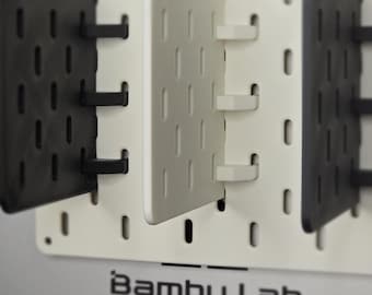 May include: White pegboard with black and white pegboard accessories. The pegboard has the text "Bambu Lab" printed on the bottom.