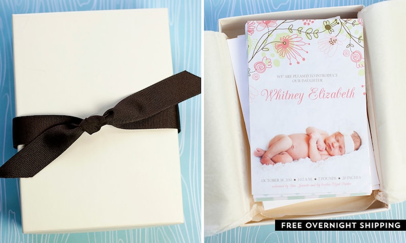 May include: A cream-colored gift box tied with a dark brown ribbon. Inside, a card announces "Whitney Elizabeth" with a photo of a newborn. Floral design in pink and green accents the card.