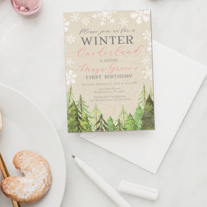 Puede incluir: Una invitaci&oacute;n con tem&aacute;tica invernal con el texto "Please join us for a WINTER Onederland to celebrate Maya Grace's FIRST BIRTHDAY." La invitaci&oacute;n presenta copos de nieve, pinos de acuarela y un fondo beige. Incluye un sobre blanco.