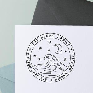 May include: A circular black and white stamp with the text "THE MUNNS FAMILY" and "8 GREEN LAKE AVE. WINONA, MN 55987". The design includes waves, stars, and a crescent moon.