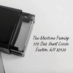 May include: A black rectangular address stamp with a clear window, partially visible. The text "The Martine Family, 570 Oak Knoll Circle, Easton, WY 82930" is printed in black cursive font.