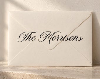 May include: A cream-colored rectangular envelope with a pointed flap, featuring the black printed text The Morrisons in a sophisticated, flowing script font centered on the front surface of the paper stationery item.
